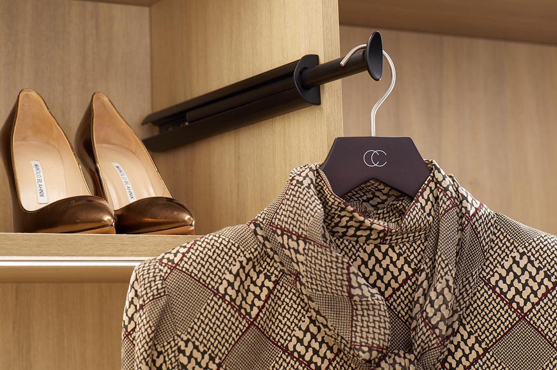 Custom open shelving with valet rod and custom drawers made by California Closets