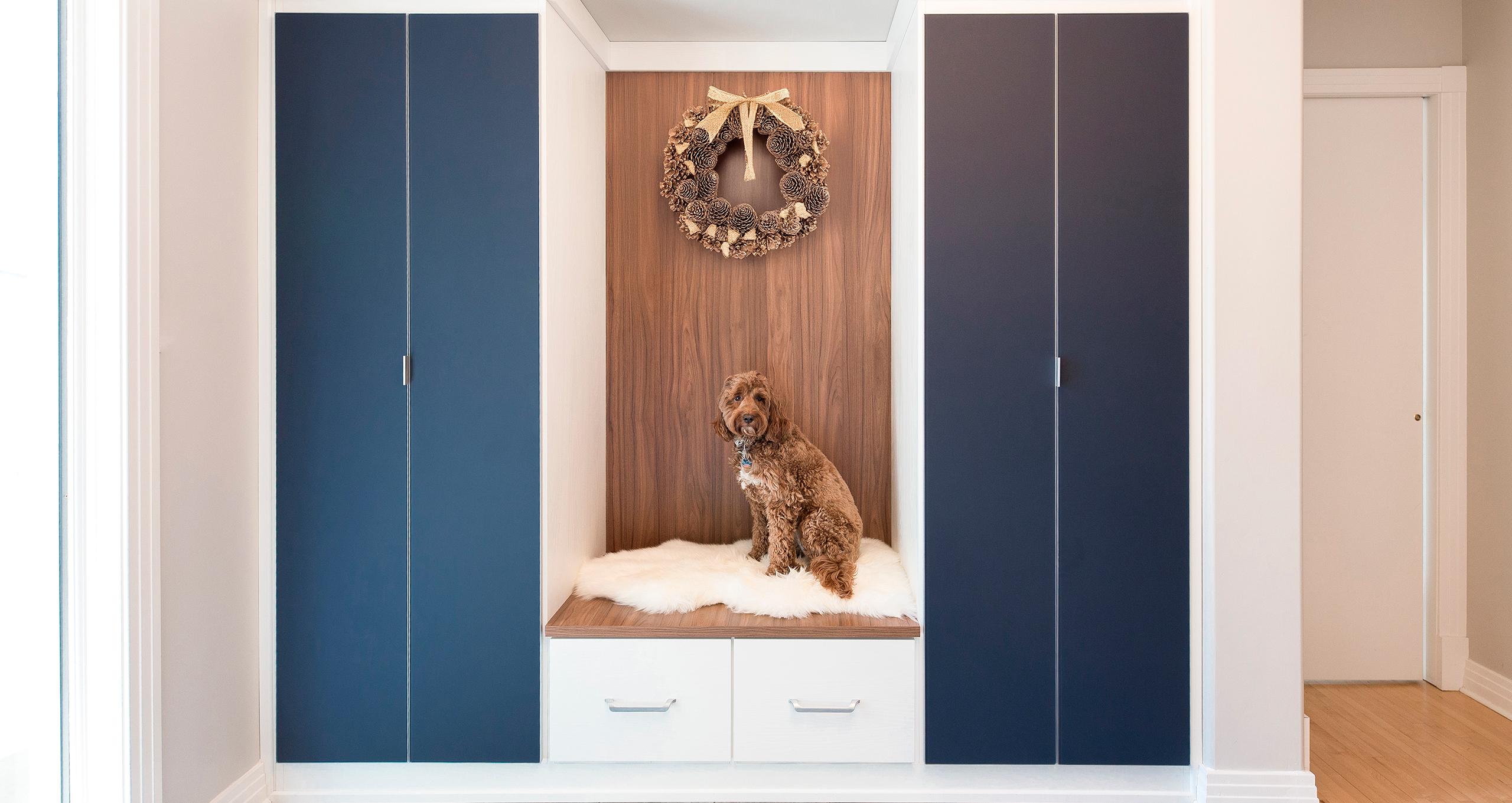 Entryway gets holiday design with a wreath hanging above custom bench and cabinets from California Closets