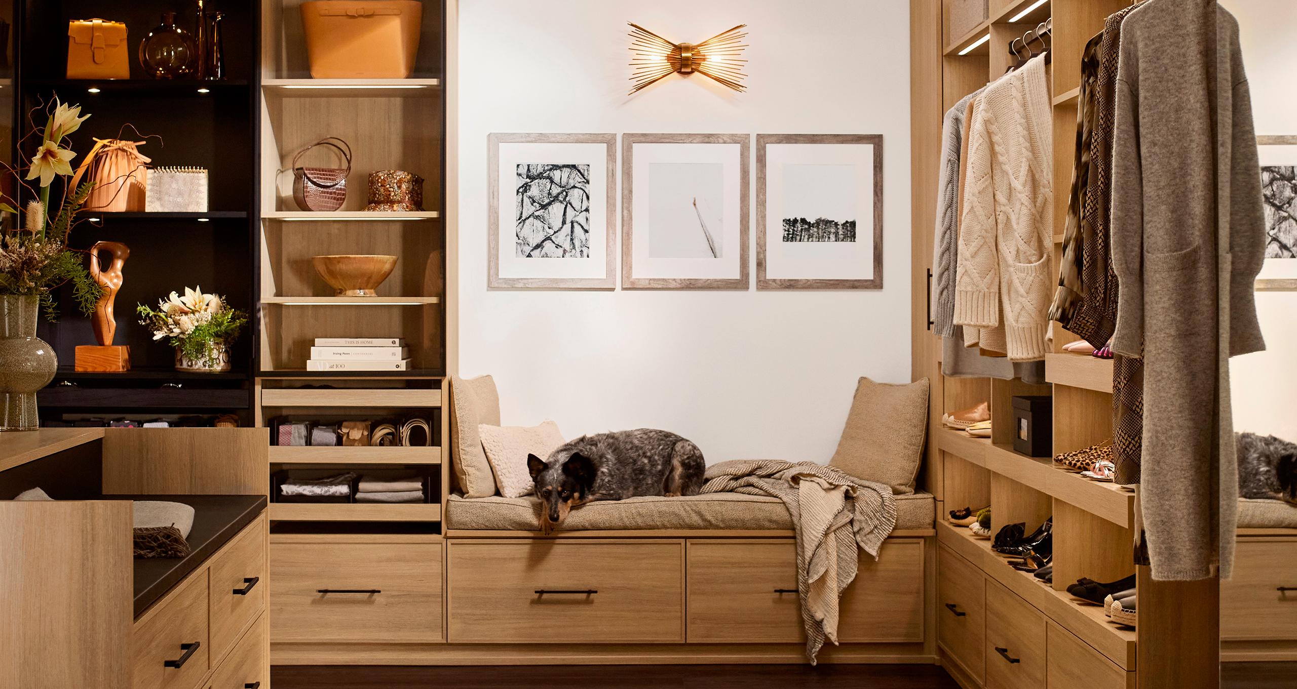 Walk in closet designed with custom shelves and doggy bed bench from California Closets