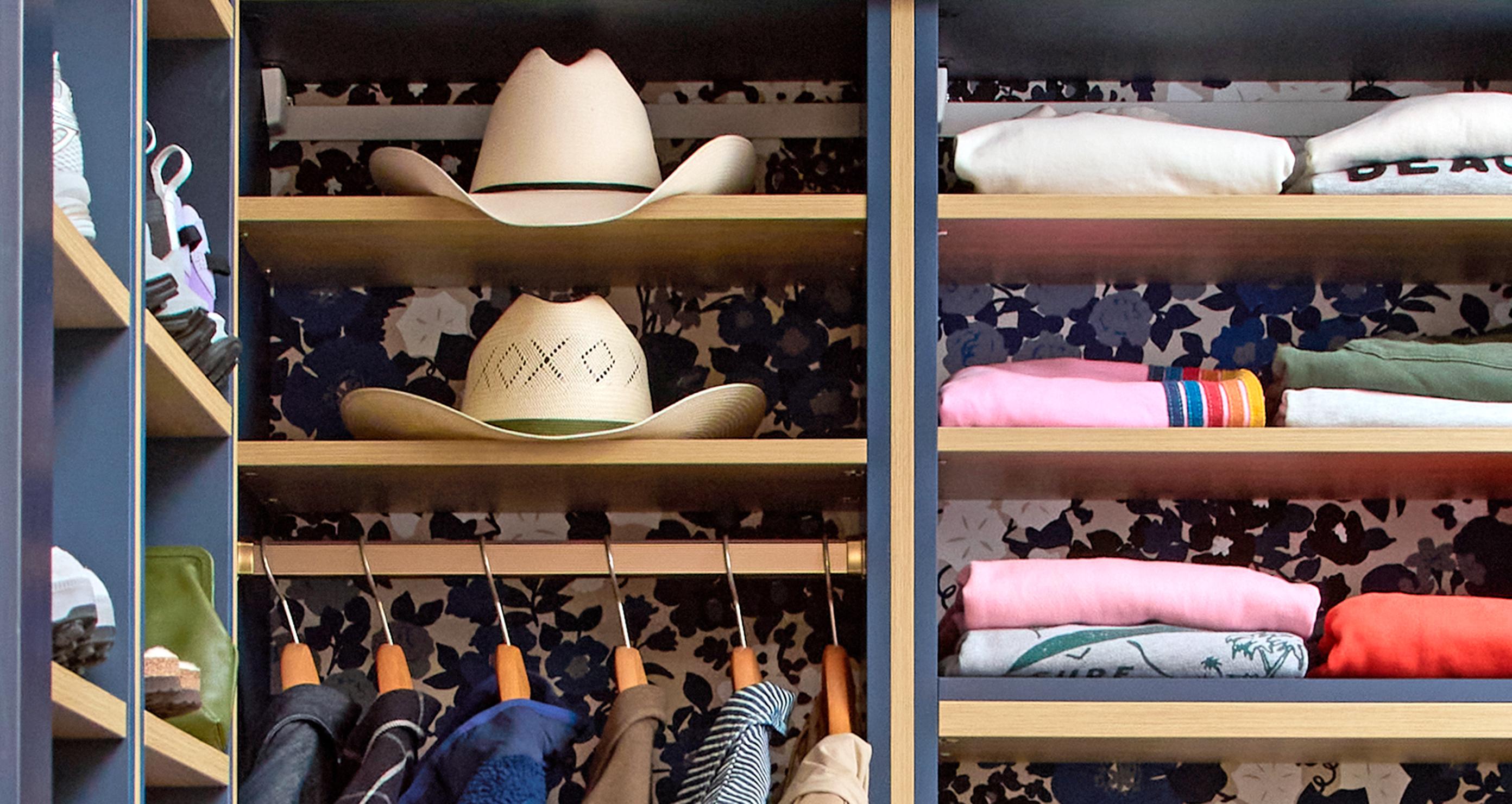 A stylish closet setup by California Closets featuring western-style hats on a shelf, neatly folded clothes above, and hanging garments below. | California Closets