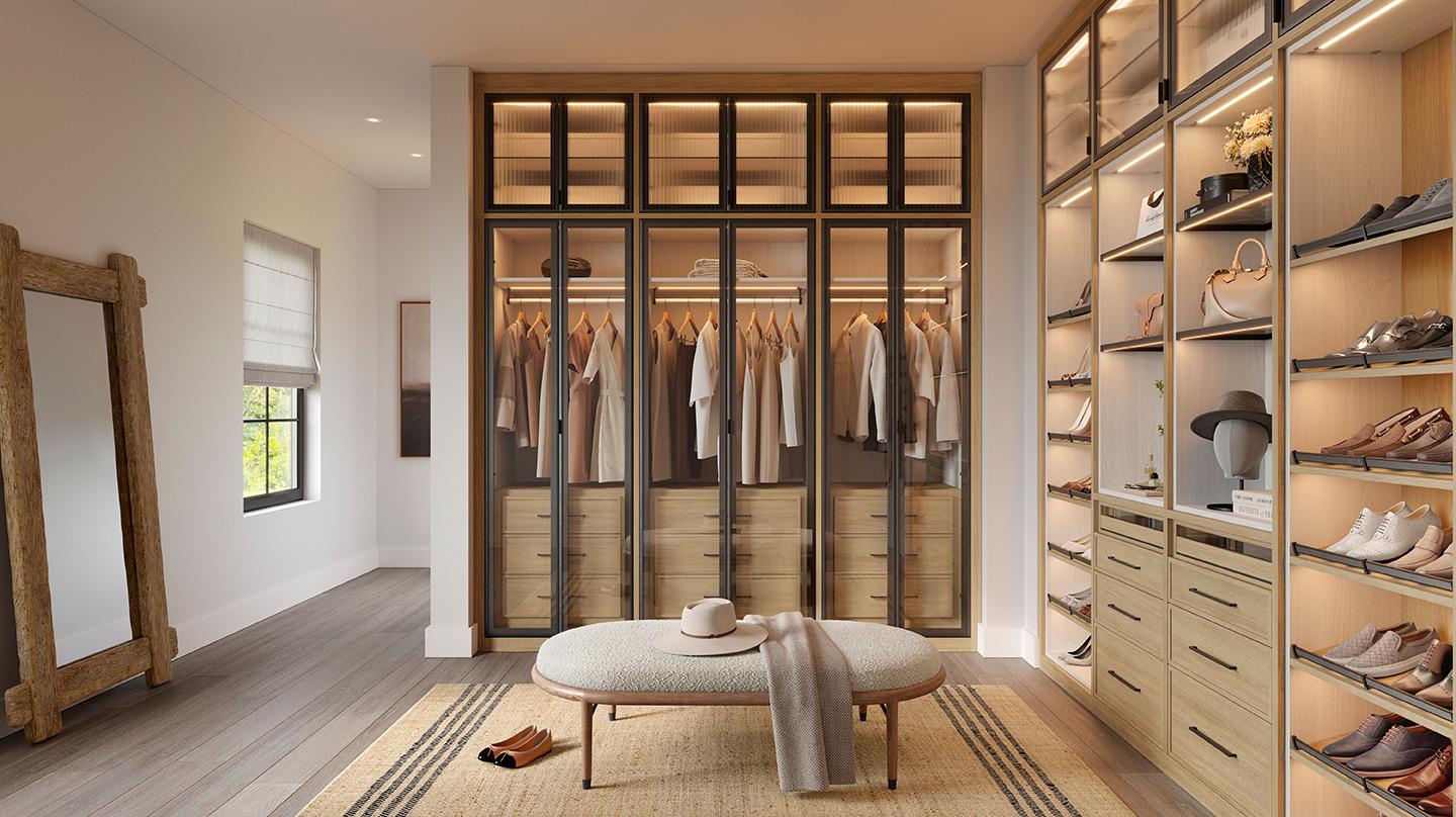 A walk in closet designed with shoe storage, custom cabinets, dresser drawers and lighting created by California Closets
