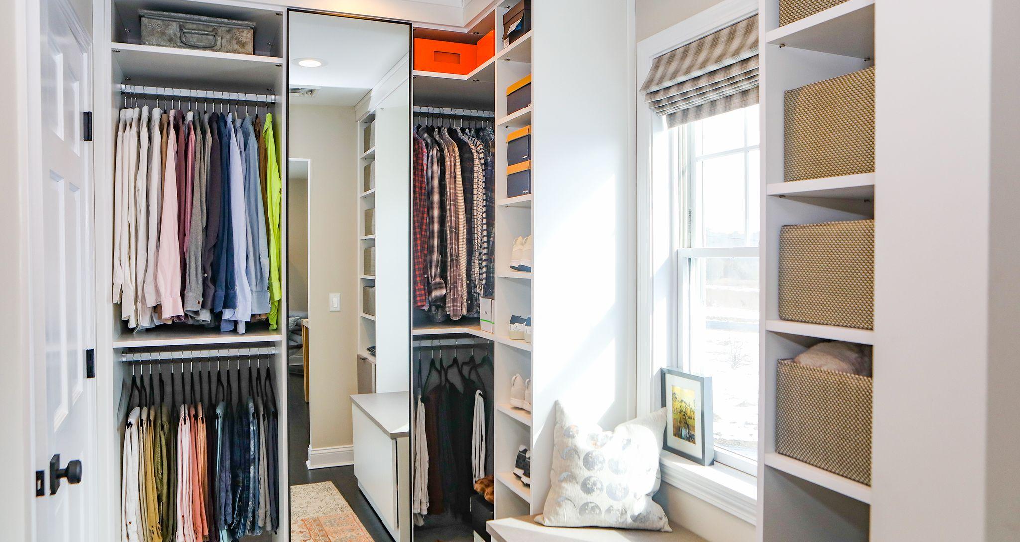 Custom closet with open shelving, hanging wardrobe and center mirror by California Closets