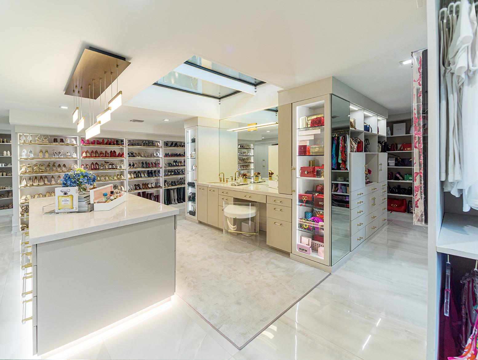 Luxe walk in closet designed for a couple with open shelving, center islands and extra hanging space by California Closets