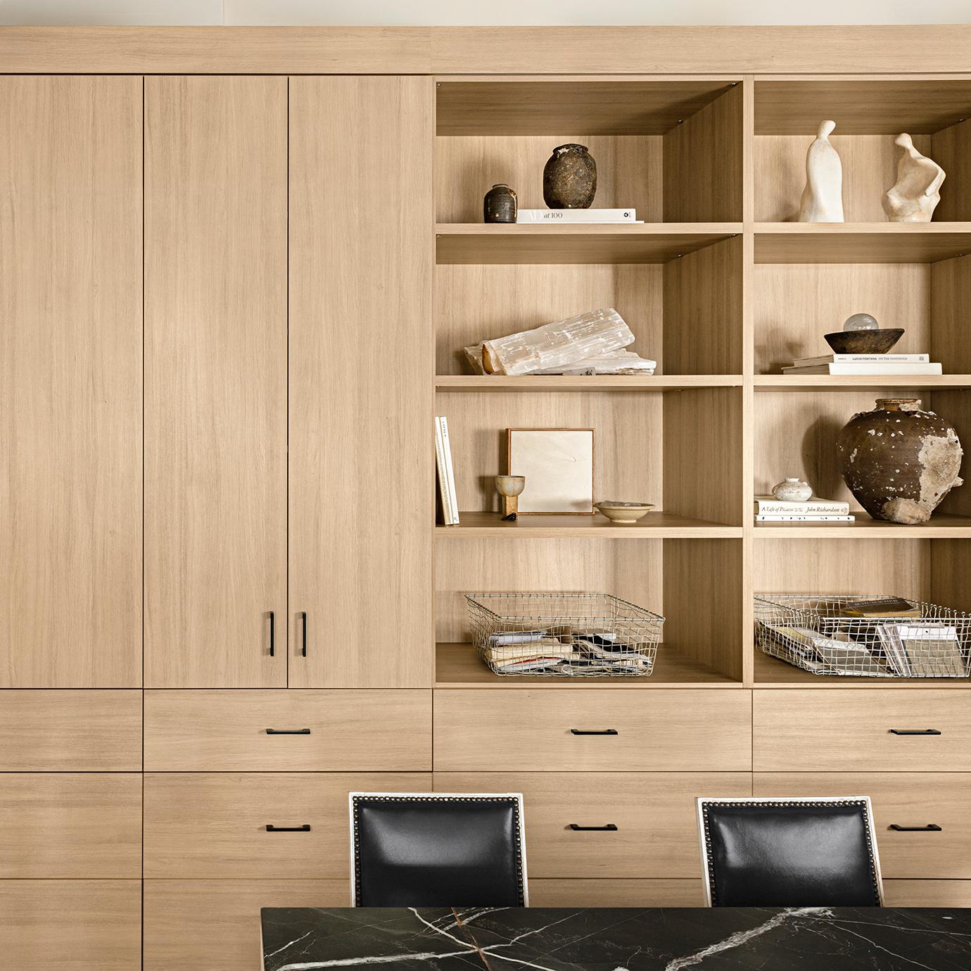 Custom bookshelves and custom cabinets and storage drawers behind conference table in light finish by California Closets
