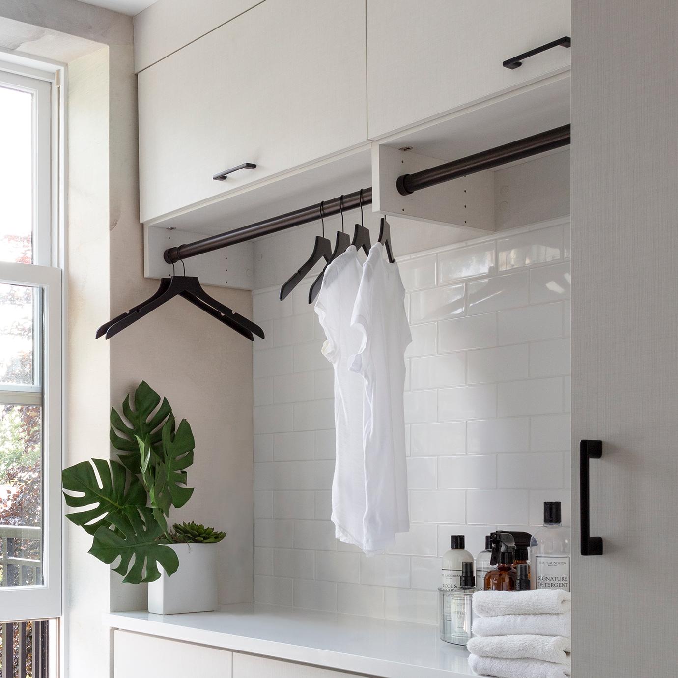 Custom laundry room with hanging poles for extra space in a white finish by California Closets